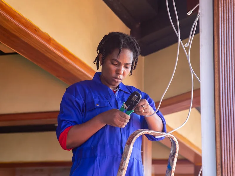 Professional electrician working on wiring in an indoor setting, demonstrating skill and concentration.