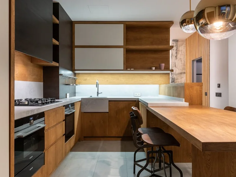 Sleek modern kitchen with wooden cabinets and pendant lamps.