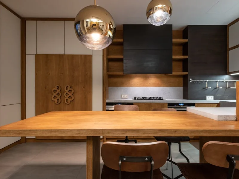 Sleek minimalist kitchen with wooden cabinetry and modern pendant lights.