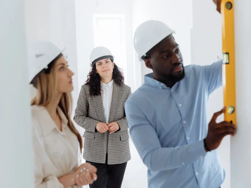 Group of diverse contractors collaborating on a construction project indoors, using a level bar