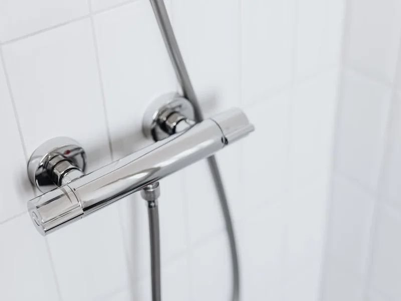 Modern chrome shower faucet on white tiled wall, elegant and clean design