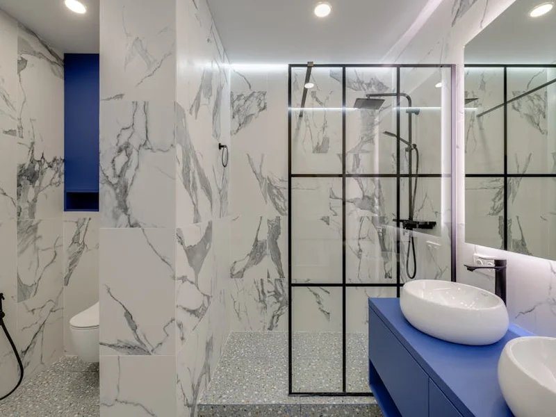 Elegant bathroom featuring marble walls, double sinks, and a glass-enclosed shower