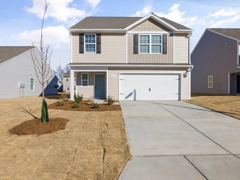 A contemporary suburban house with a spacious driveway and garage under a clear sky.