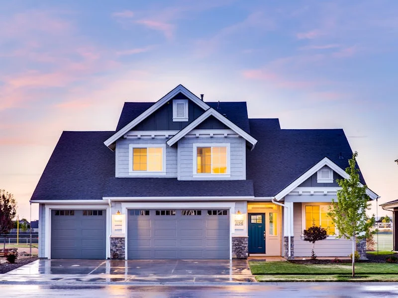 Beautiful two-story house with illuminated windows and garage at dusk.