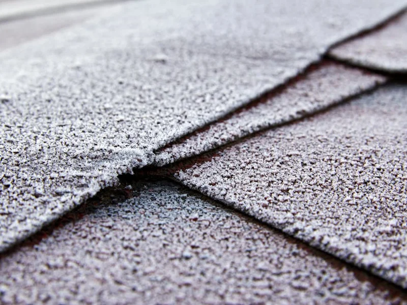 Close-up view of frost-covered roof shingles showcasing texture and cold weather effects.
