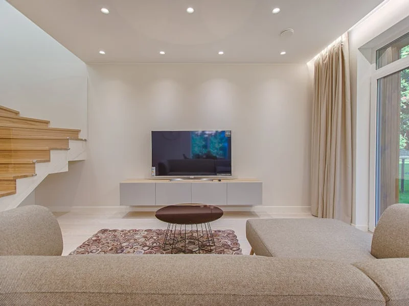Contemporary living room with stylish sofa, TV, and staircase, offering a cozy interior design setting.
