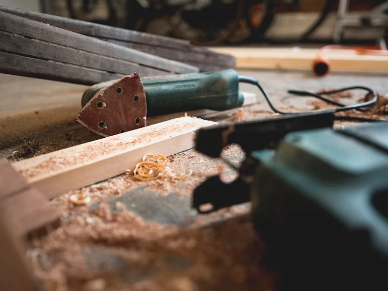 Close-up of various woodworking tools in a workshop, featuring wood shavings and equipment.